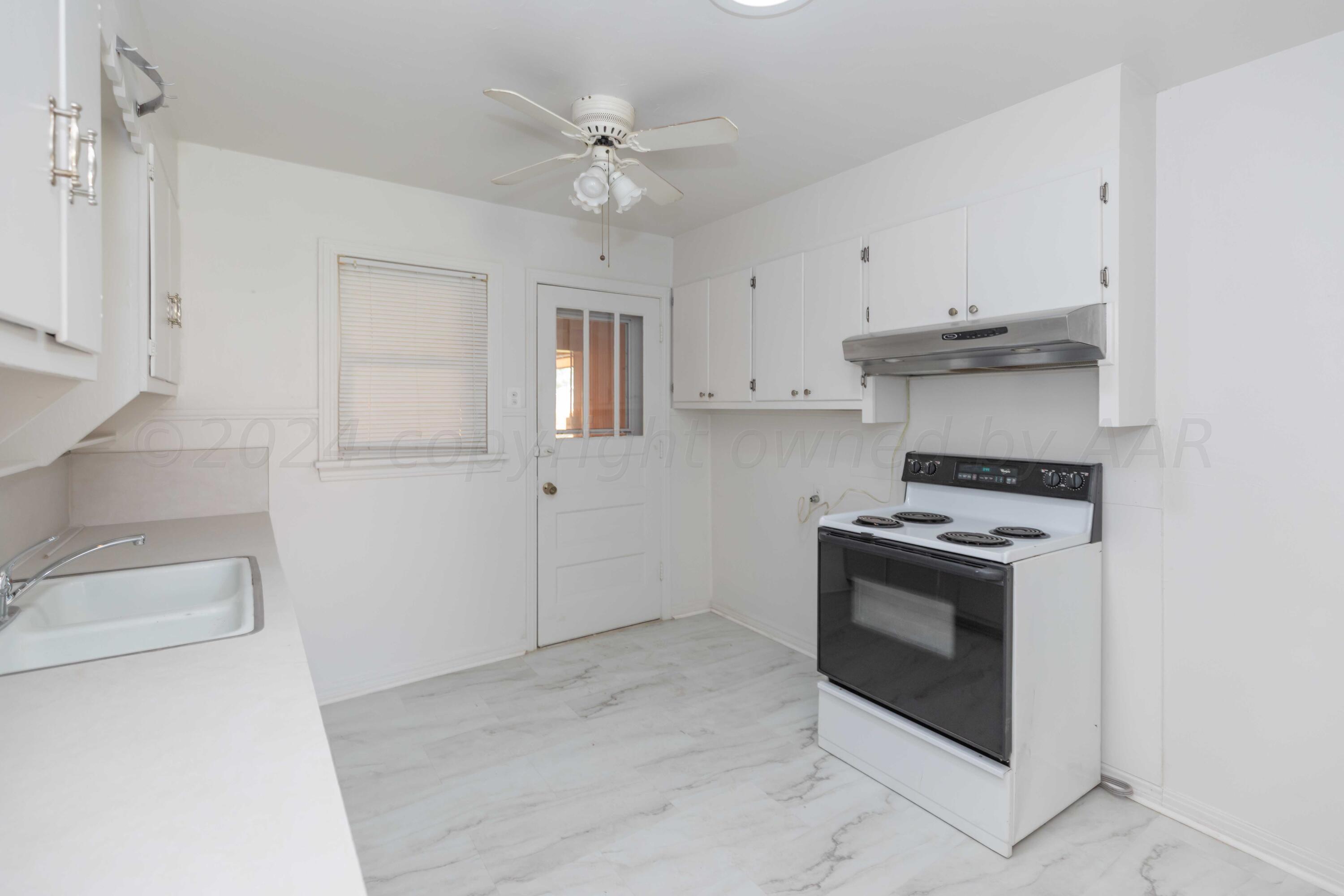 1613 South Travis Street Amarillo, TX 79102 - Photo 14 of 49 a kitchen with a stove oven and white cabinets