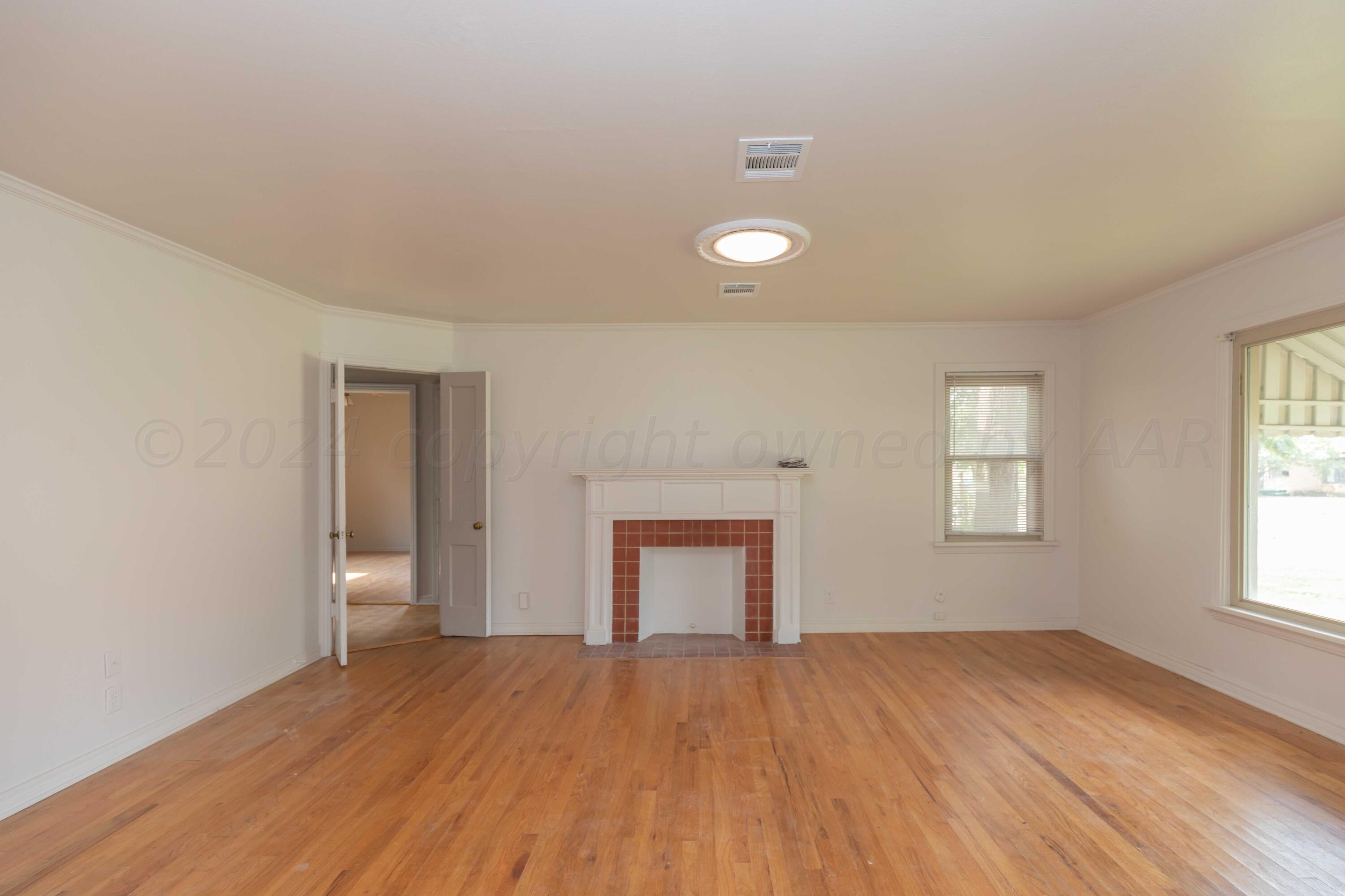 1613 South Travis Street Amarillo, TX 79102 - Photo 6 of 49 an empty room with wooden floor and windows