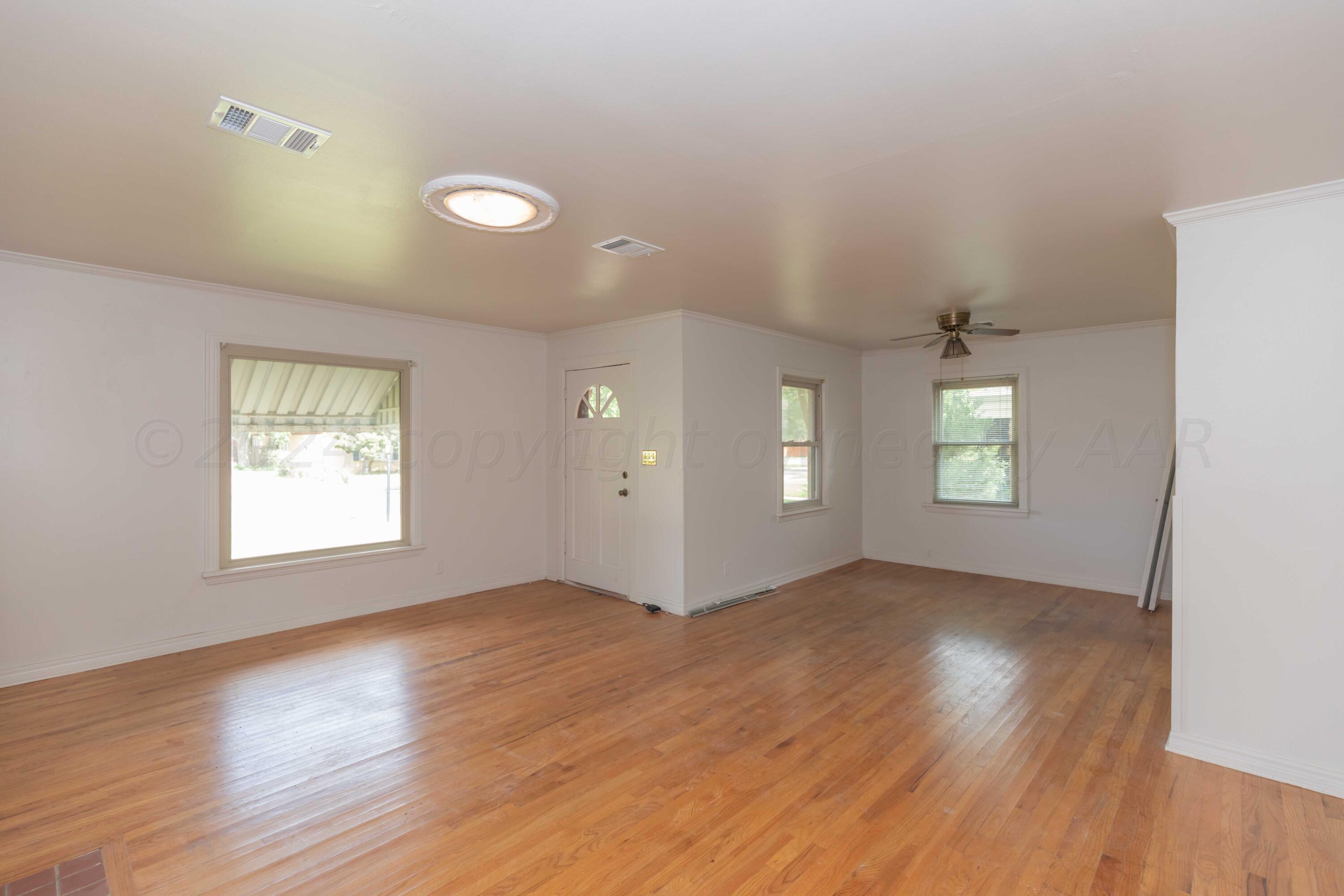 1613 South Travis Street Amarillo, TX 79102 - Photo 8 of 49 an empty room with wooden floor and windows