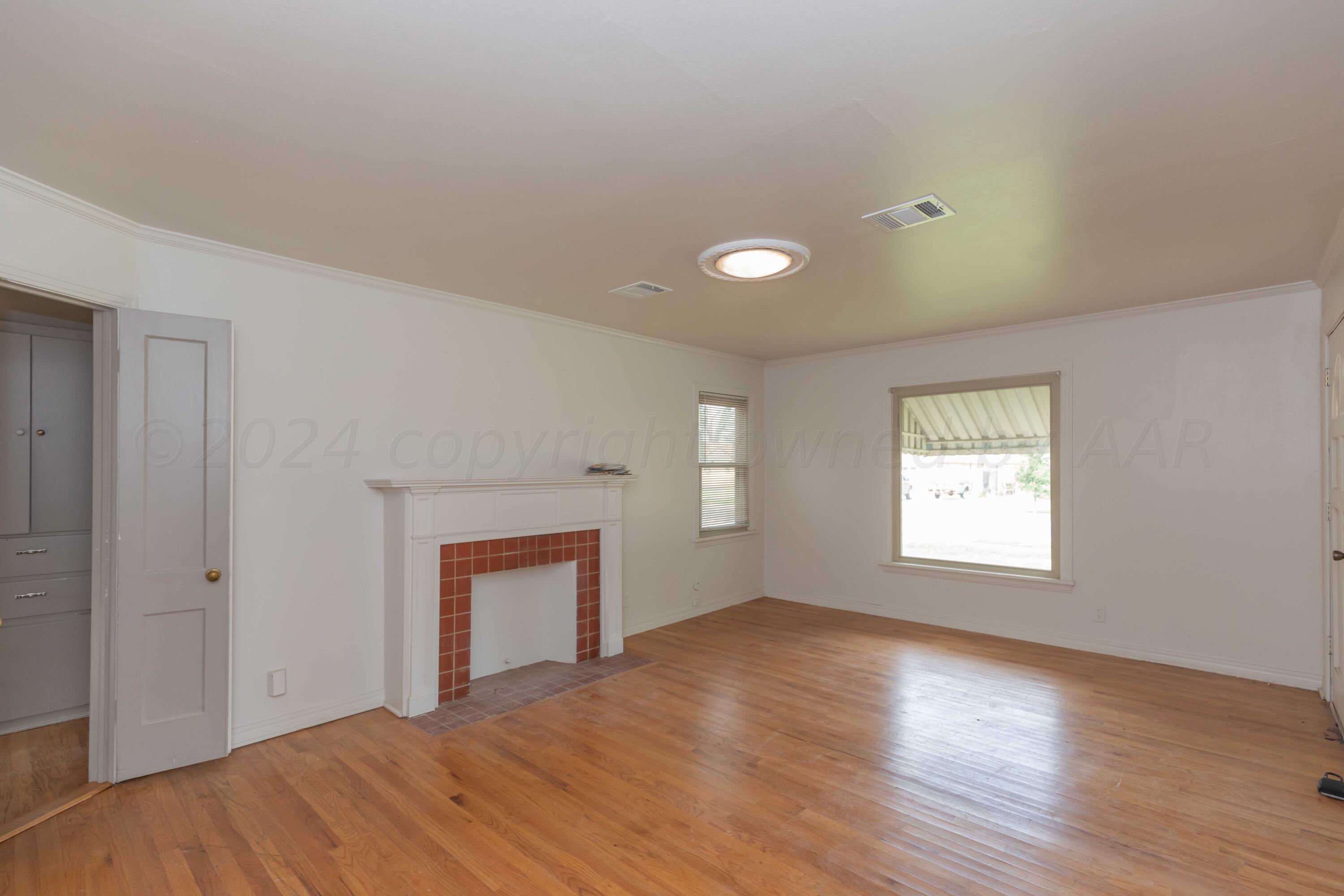 1613 South Travis Street Amarillo, TX 79102 - Photo 9 of 49 a view of an empty room with a window and wooden floor