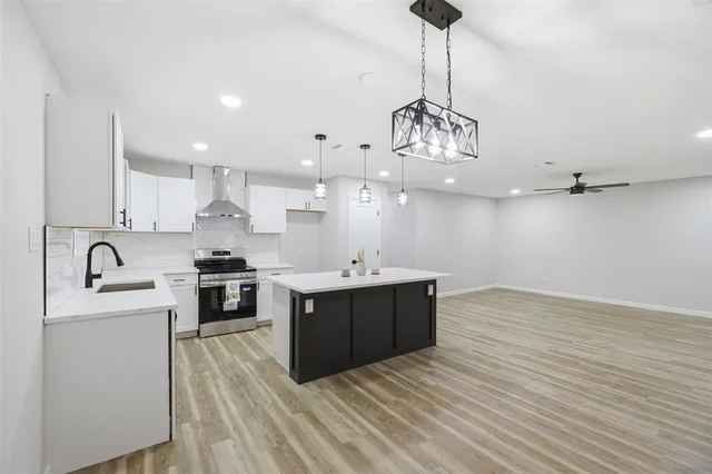 a large kitchen with stainless steel appliances granite countertop a sink dishwasher a stove and white countertops with wooden floor