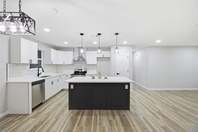 a large white kitchen with a sink and dishwasher stove a refrigerator with wooden floor