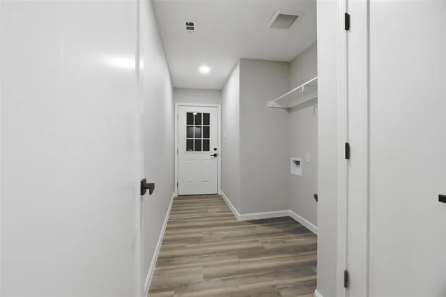 a view of a hallway with wooden floor and a bathroom