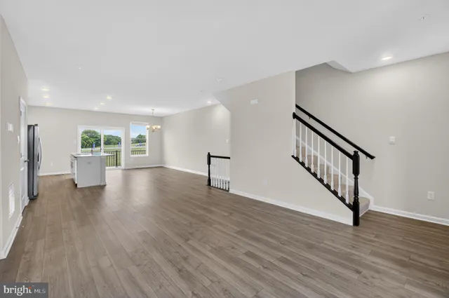 a view of an empty room with wooden floor and a living room