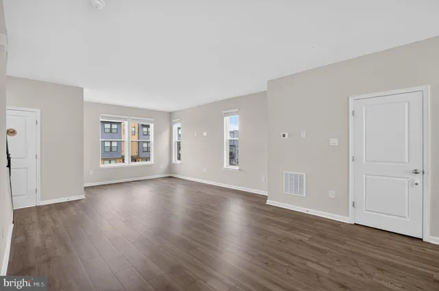 a view of an empty room with wooden floor and windows