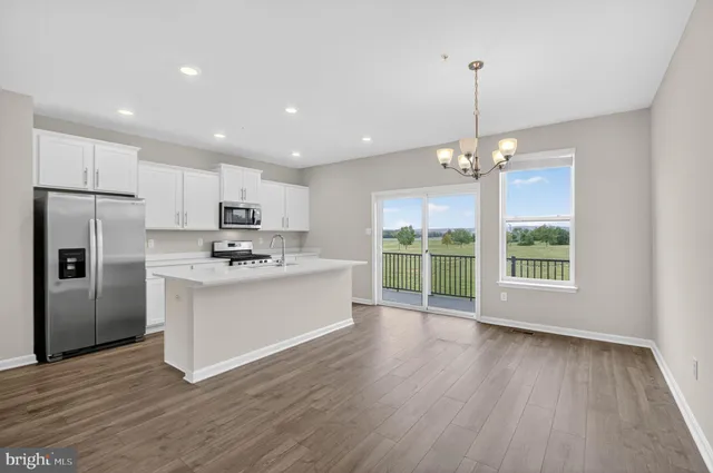 a kitchen with stainless steel appliances granite countertop a refrigerator a sink dishwasher a stove and a large window with wooden floor