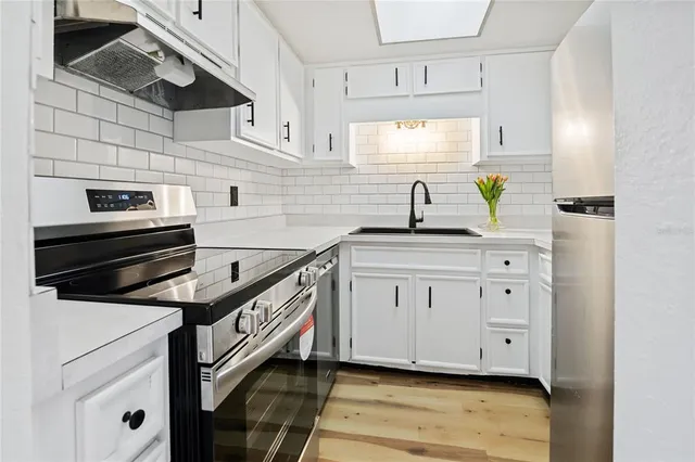 a kitchen with granite countertop a sink a stove and cabinets