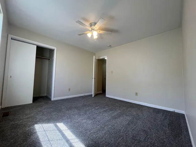 an empty room with closet and a chandelier fan