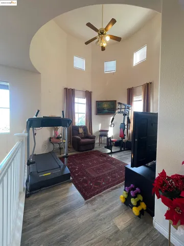 a hallway with white cabinets and couches with wooden floor
