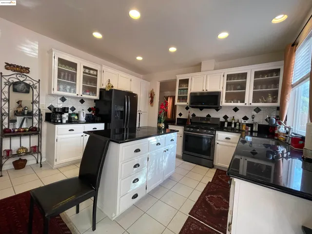 a kitchen with granite countertop a refrigerator stove microwave and sink