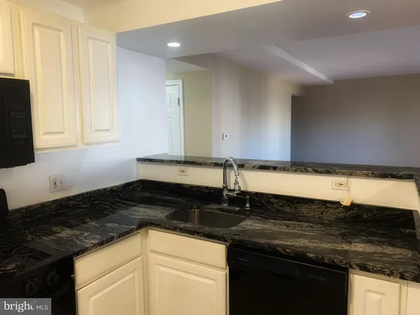 a kitchen with granite countertop stainless steel appliances a sink a stove wooden floor and cabinets