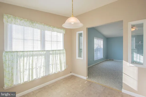 an empty room with chandelier fan and windows