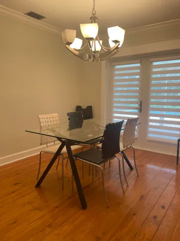 a dining room with wooden floor a chandelier a glass table and chairs