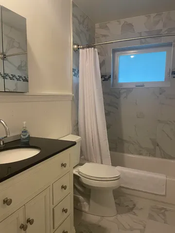 a bathroom with a granite countertop sink toilet and shower