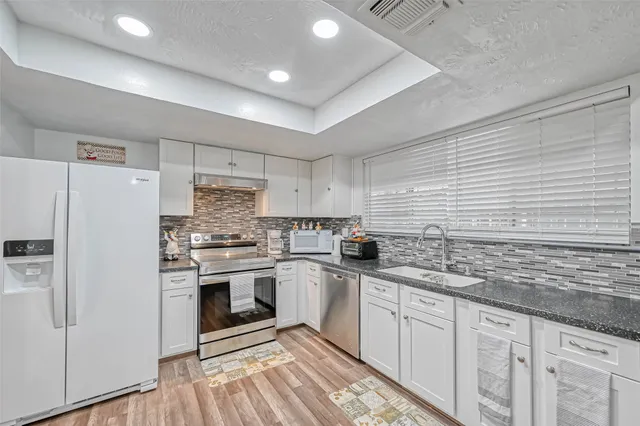 a kitchen with white cabinets stainless steel appliances and sink