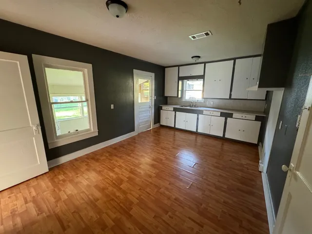 a view of an empty room with window and wooden floor