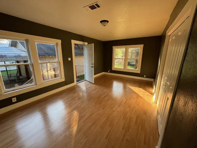 a view of an empty room with a window and wooden floor