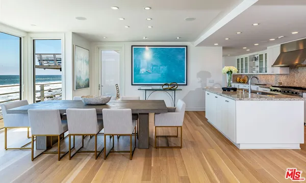 a kitchen with stainless steel appliances granite countertop a table chairs sink and wooden floor
