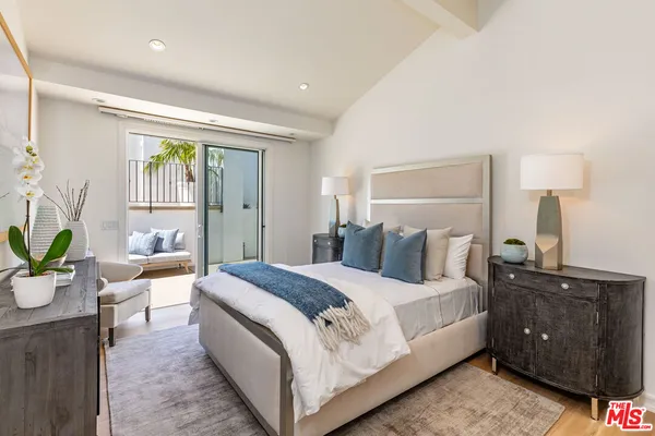 a spacious bedroom with a large bed and a potted plant