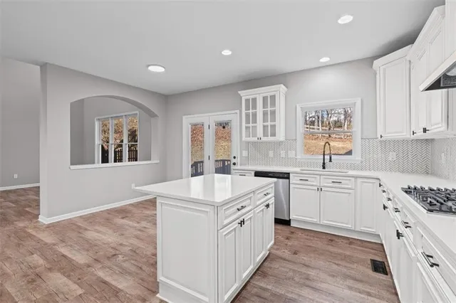 a kitchen with stainless steel appliances granite countertop a stove and white cabinets