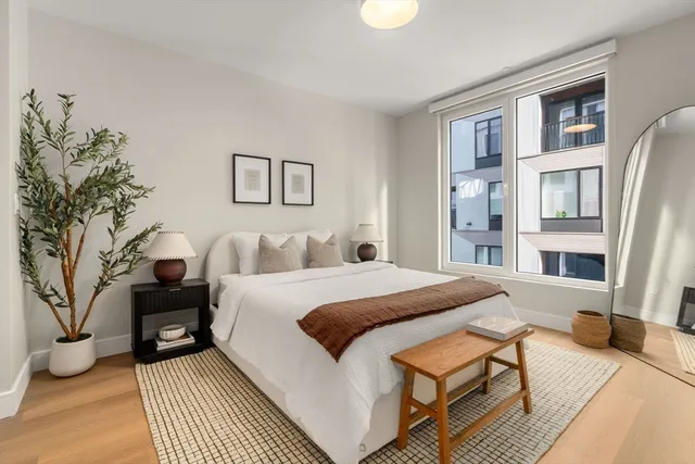 a spacious bedroom with a bed a couch and a potted plant