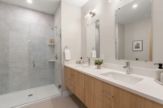 a bathroom with a double vanity sink mirror and shower