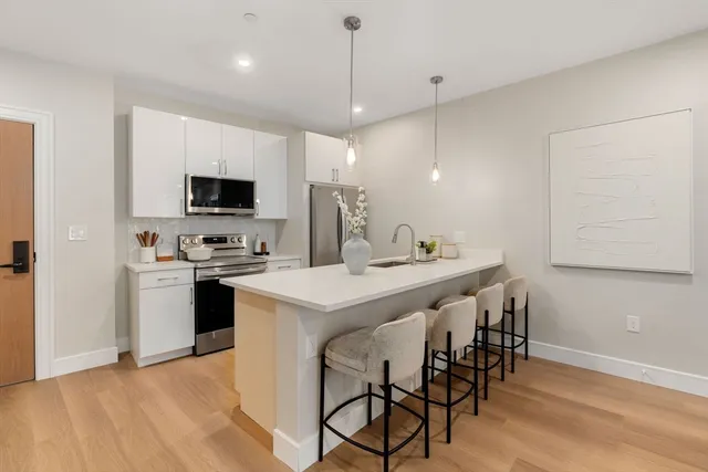 a kitchen with stainless steel appliances kitchen island a white cabinets and chairs