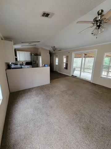 a view of a big room with windows and chandelier fan