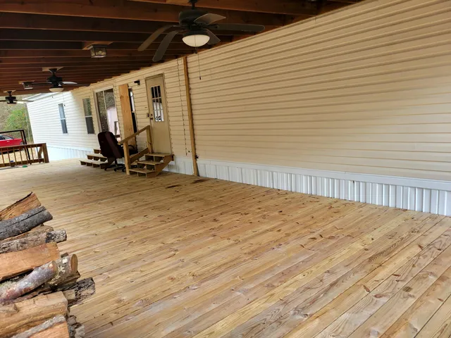 a view of wooden house with a deck and furniture