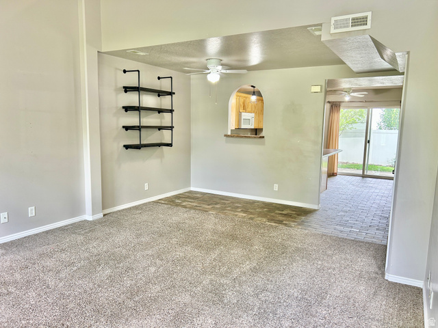 672 West 720 South Logan, UT 84321 - Photo 3 of 15 Living area featuring textured carpet flooring, a built-in industrial-style shelving unit, and a pass-through window with a stone-finish countertop