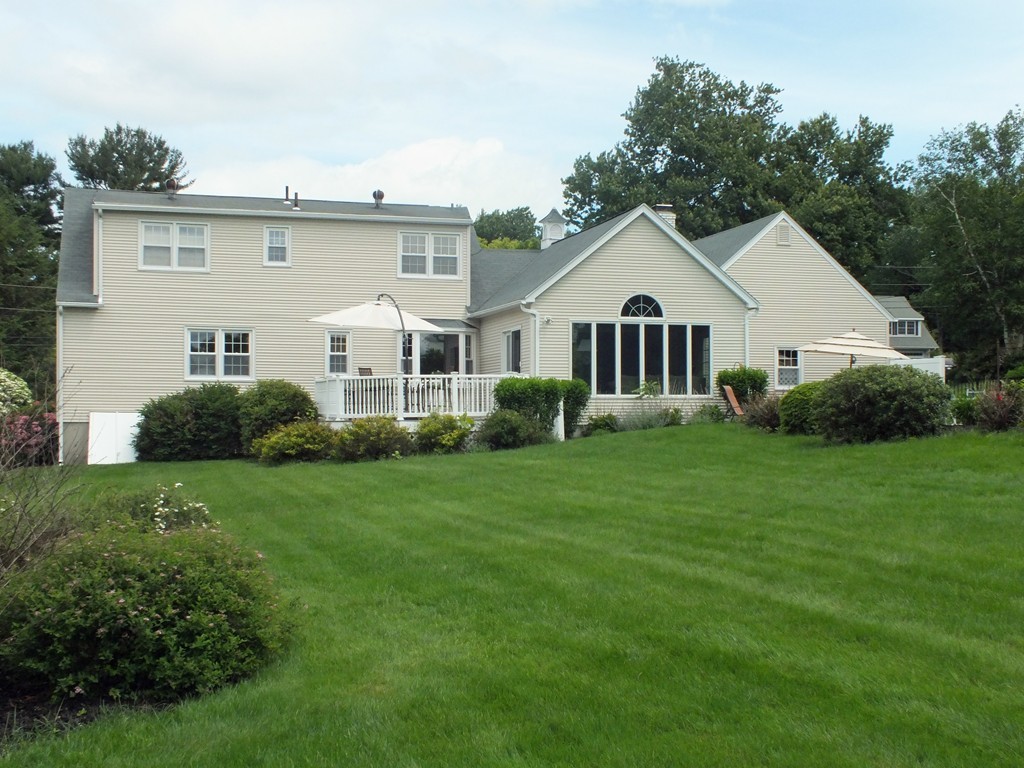 a view of a house with a big yard and large trees
