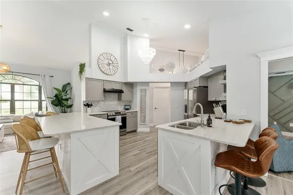 a kitchen with stainless steel appliances kitchen island granite countertop a stove a sink a dining table and chairs with wooden floor
