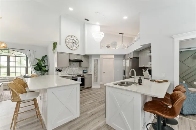 a kitchen with stainless steel appliances kitchen island granite countertop a stove a sink a dining table and chairs with wooden floor