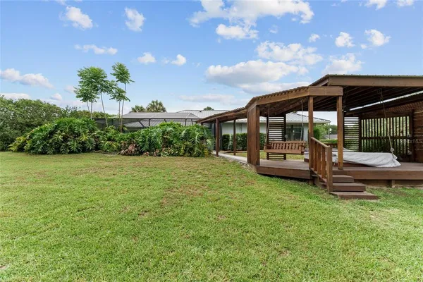 a view of a patio with table and chairs under an umbrella with large trees