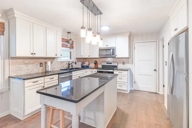 a kitchen with kitchen island granite countertop a sink cabinets stainless steel appliances and a counter top space