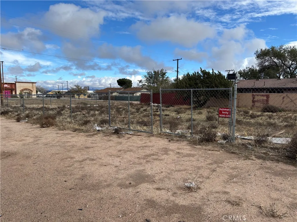 a view of a dry yard with wooden fence