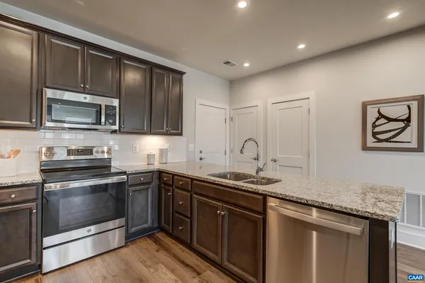 a kitchen with stainless steel appliances granite countertop a refrigerator a stove and a sink