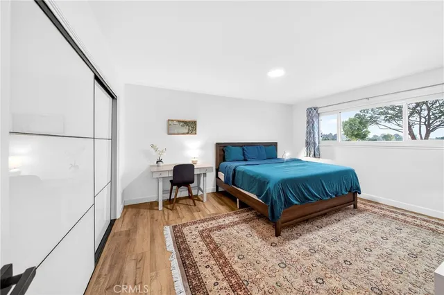 a bedroom with a bed table chair and a large window