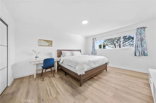 a bedroom with a bed table chair and a wall painting