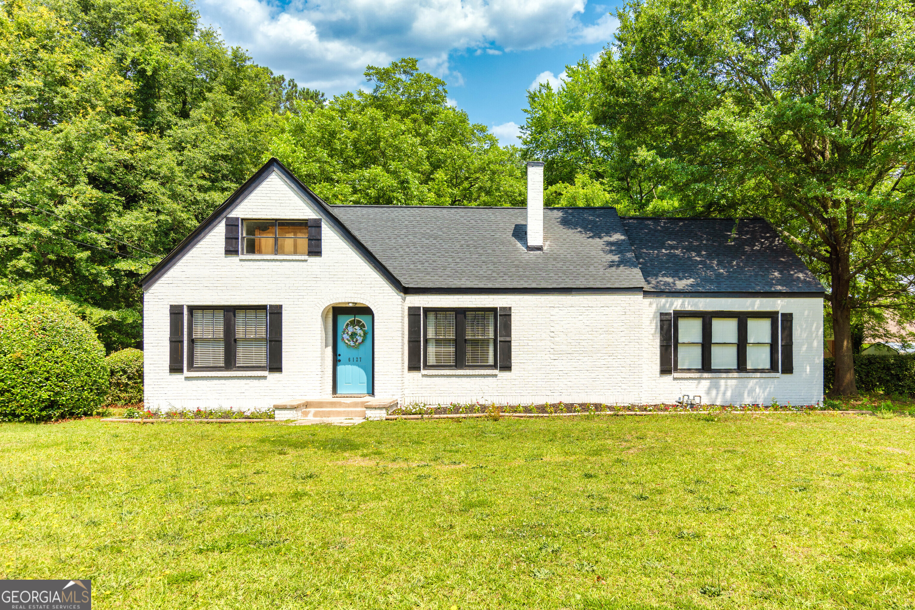 a front view of house with yard and trees in the background