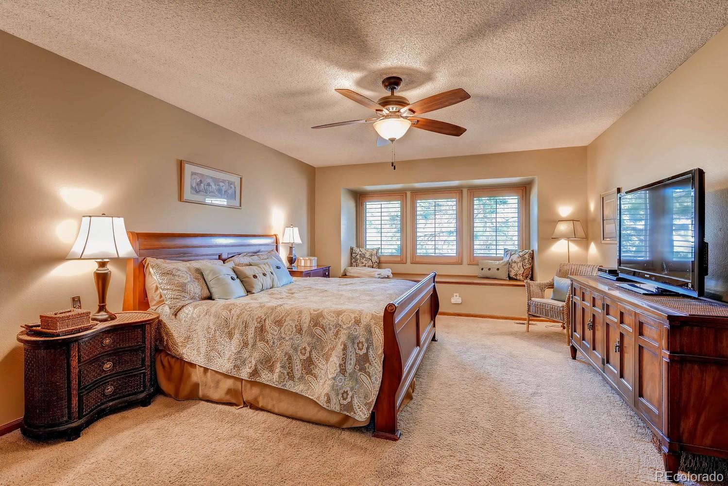 8110 Sweet Water Road Lone Tree, CO 80124 - Photo 19 of 34 a spacious bedroom with a bed and a flat screen tv