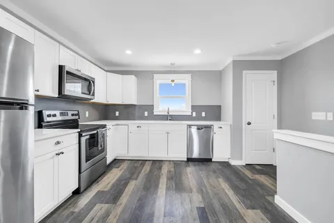a kitchen with a sink cabinets and wooden floor