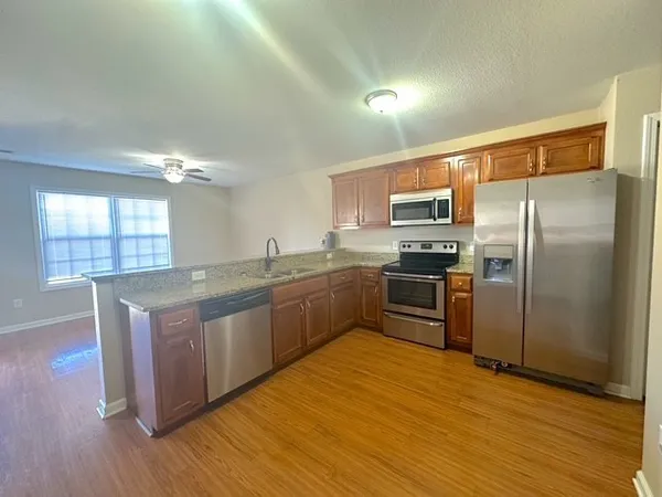 a kitchen with stainless steel appliances granite countertop a refrigerator a sink dishwasher a stove with wooden floors