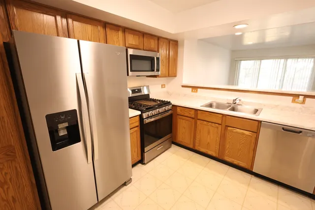 a kitchen with stainless steel appliances a refrigerator a sink a stove a microwave a sink a refrigerator and cabinets