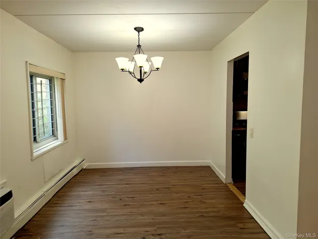 an empty room with wooden floor chandelier and windows