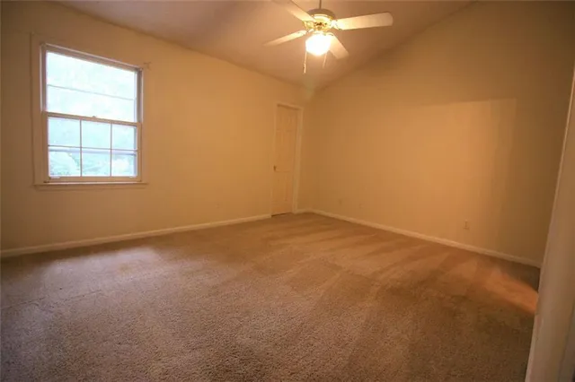 an empty room with a chandelier fan and windows
