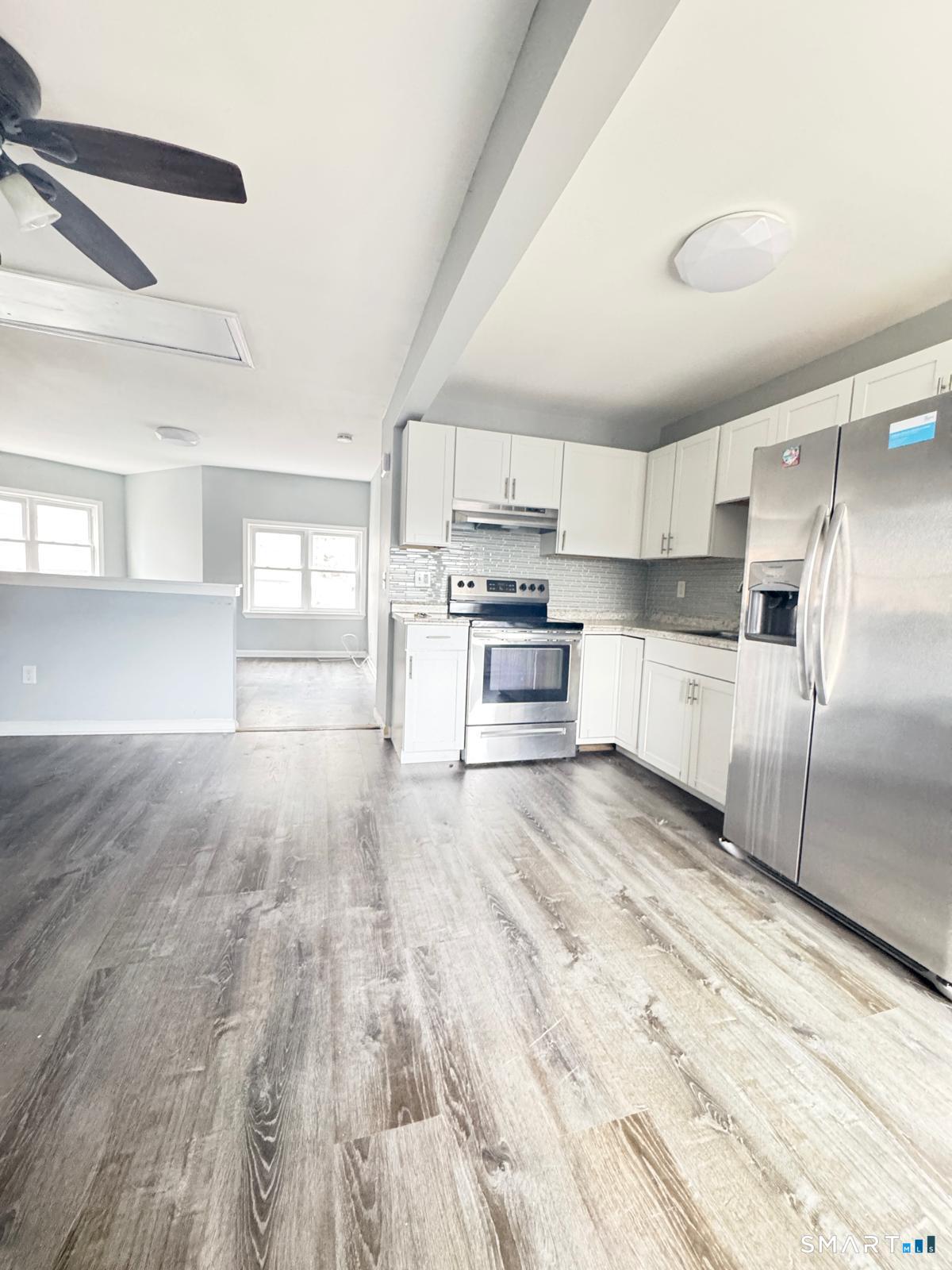 a kitchen with granite countertop a refrigerator and a stove top oven