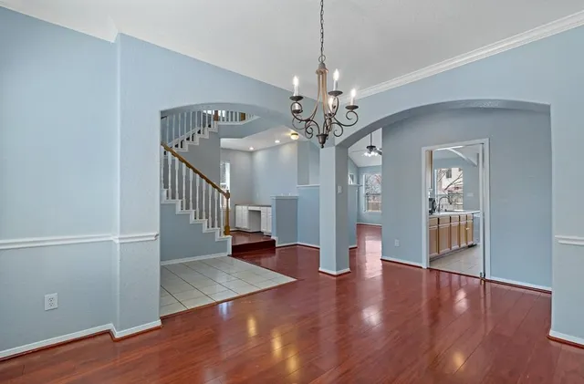 a view of a livingroom with wooden floor staircase and a kitchen space