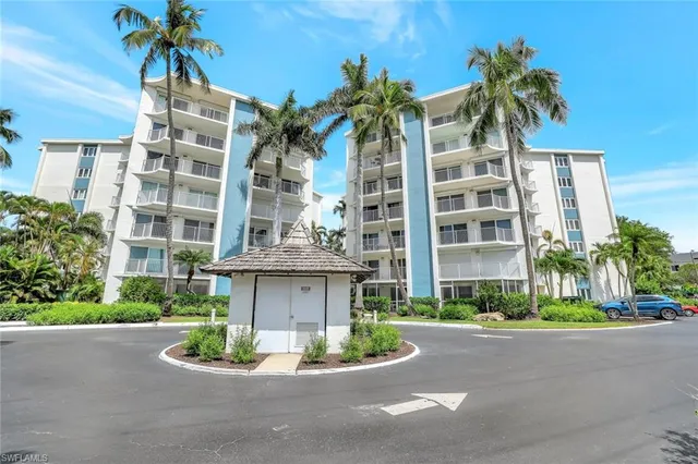 a front view of a multi story residential apartment building with yard and bench