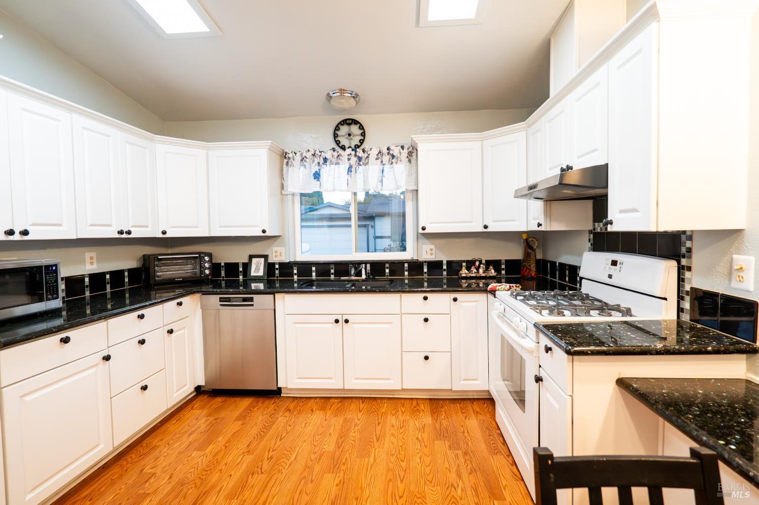 2555 Flosden Road, Unit 117 American Canyon, CA 94503 - Photo 7 of 36 a kitchen with granite countertop white cabinets and white appliances